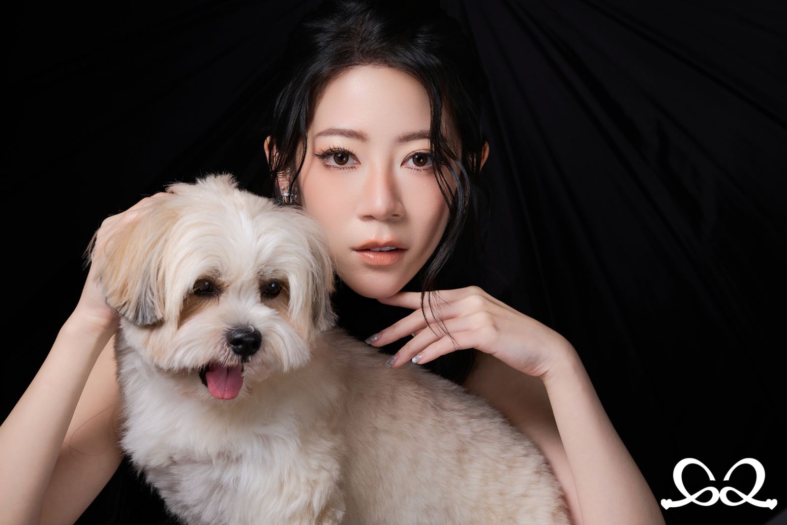 A studio portrait — a woman and her small white dog against a black ground