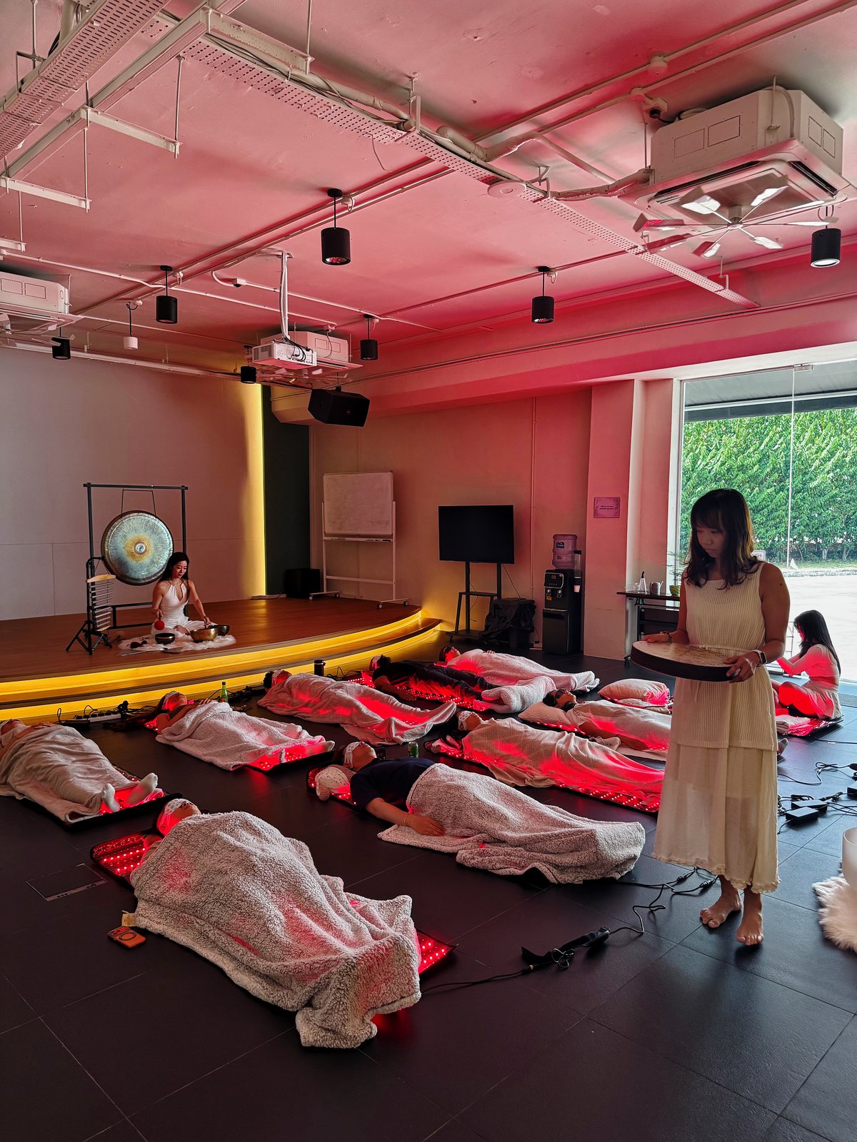 A One Moment group sound bath — guests resting on infrared mats while the crystal singing bowls are played